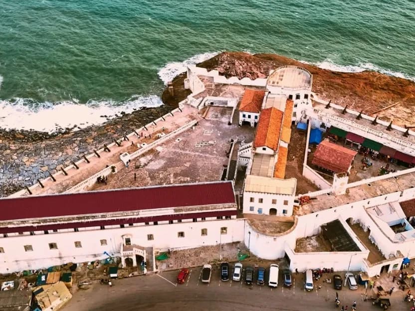 An aerial view of Cape Coast Castle on the rocky shore, with the sea behind it