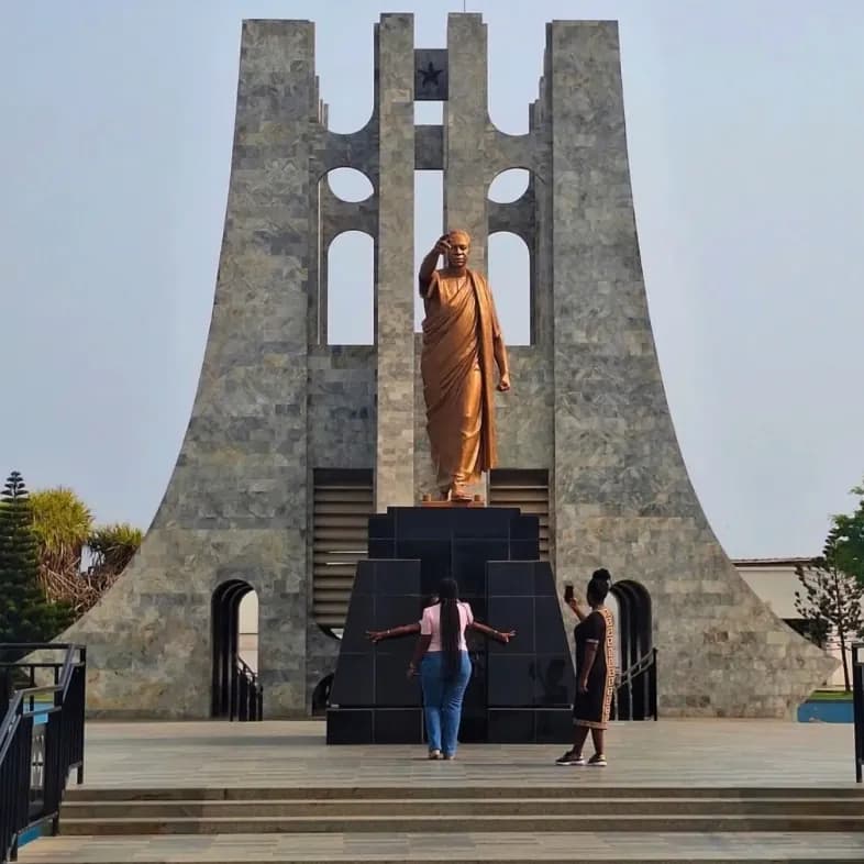 Two visitors stand before the Kwame Nkrumah Mausoleum and its bronze statue in Accra