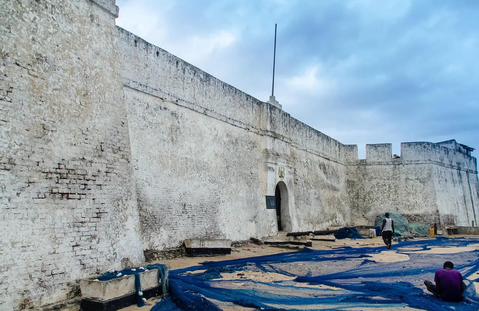 The whitewashed walls and gateway of Fort William in Anomabo, with fishing nets spread on the sand